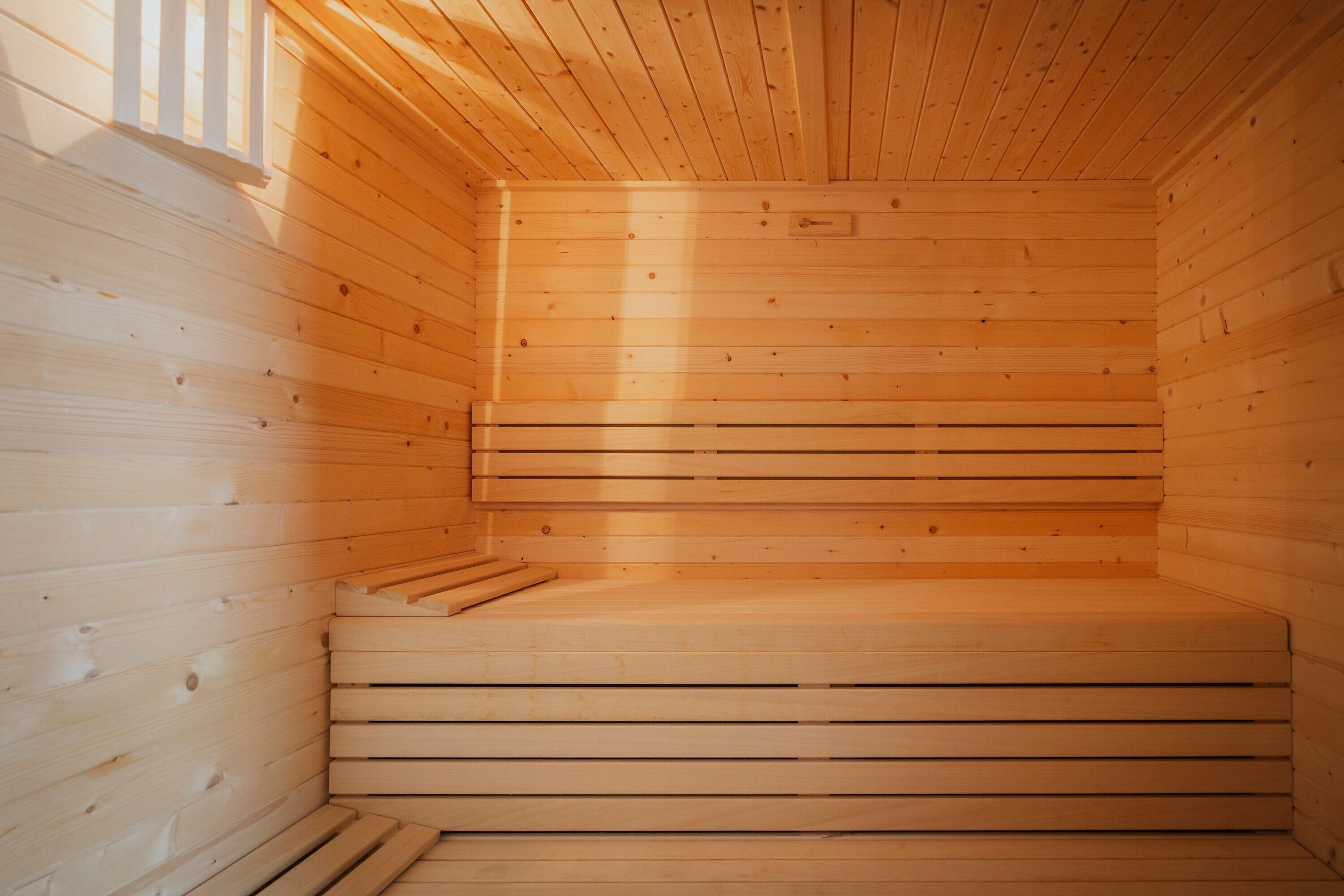 Una sauna de madera con bancos y una ventana.