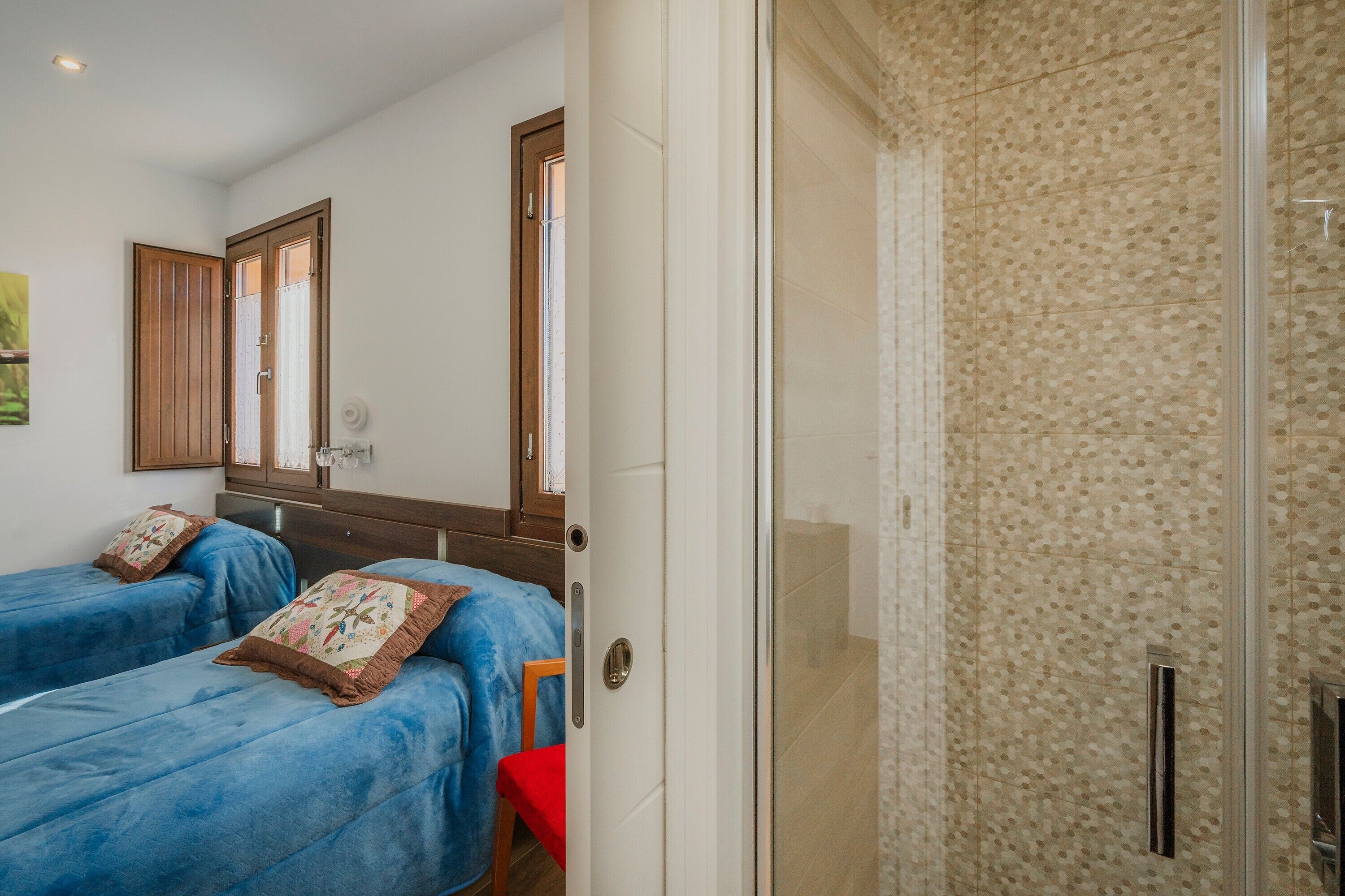 Een kamer met twee bedden, een douche en een houten deur.