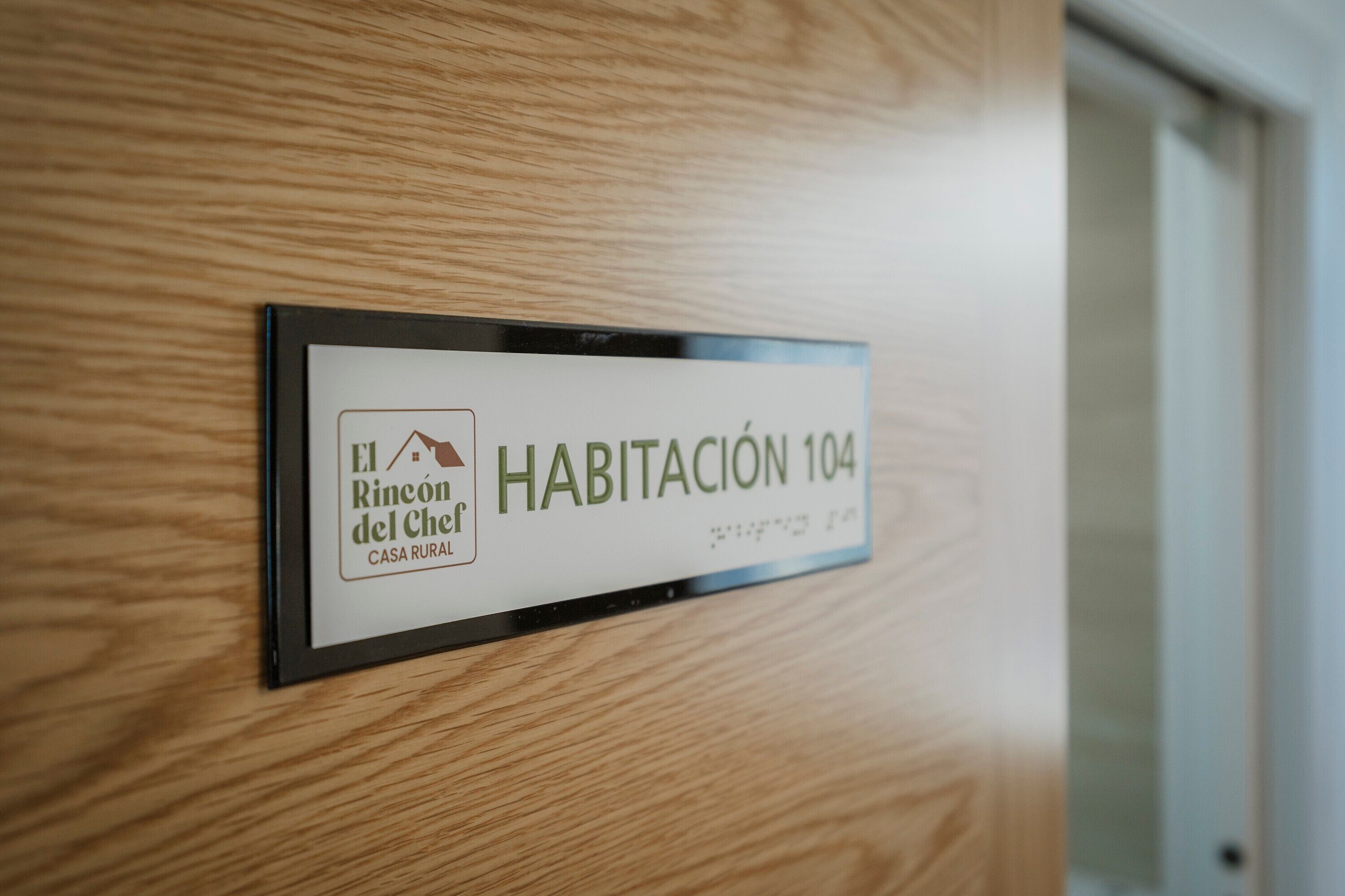 Ein Schild mit der Aufschrift 'Habitación 104' in einem Holzambiente.