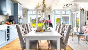 A dining area with a white table, grey upholstered chairs, and a chandelier. - La petite maison bleue (Wandlitz OT Zerpenschleuse)
