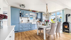 A modern kitchen with blue cabinets, a white dining table, and a wood floor. - La petite maison bleue (Wandlitz OT Zerpenschleuse)