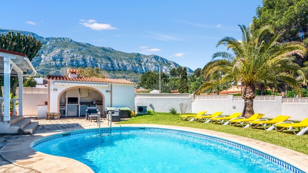 Ein Swimmingpool mit Bergblick, einer überdachten Terrasse und gelben Liegestühlen.