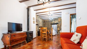 Una sala de estar con televisor, muebles de madera, chimenea y pared de piedra.
