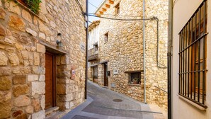 Un estrecho callejón de piedra con una puerta de madera y una ventana con barrotes.
