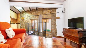 Una sala de estar con pared de piedra, un mueble bajo de televisión de madera y un sofá rojo.