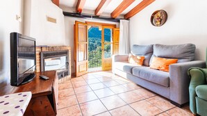 Un salon avec une cheminée, un canapé, un téléviseur et une vue sur l’extérieur.