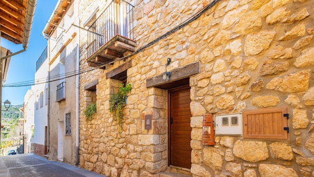 Un estrecho callejón con edificios de piedra, balcones de madera y un camino adoquinado.