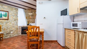 Una cocina con pared de piedra, chimenea, mesa de comedor de madera y microondas.