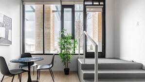 A modern interior with a staircase, a dining area with a table and chairs, and a potted plant. - Sophari Downtown: Bellevue Apartments (Bellevue)