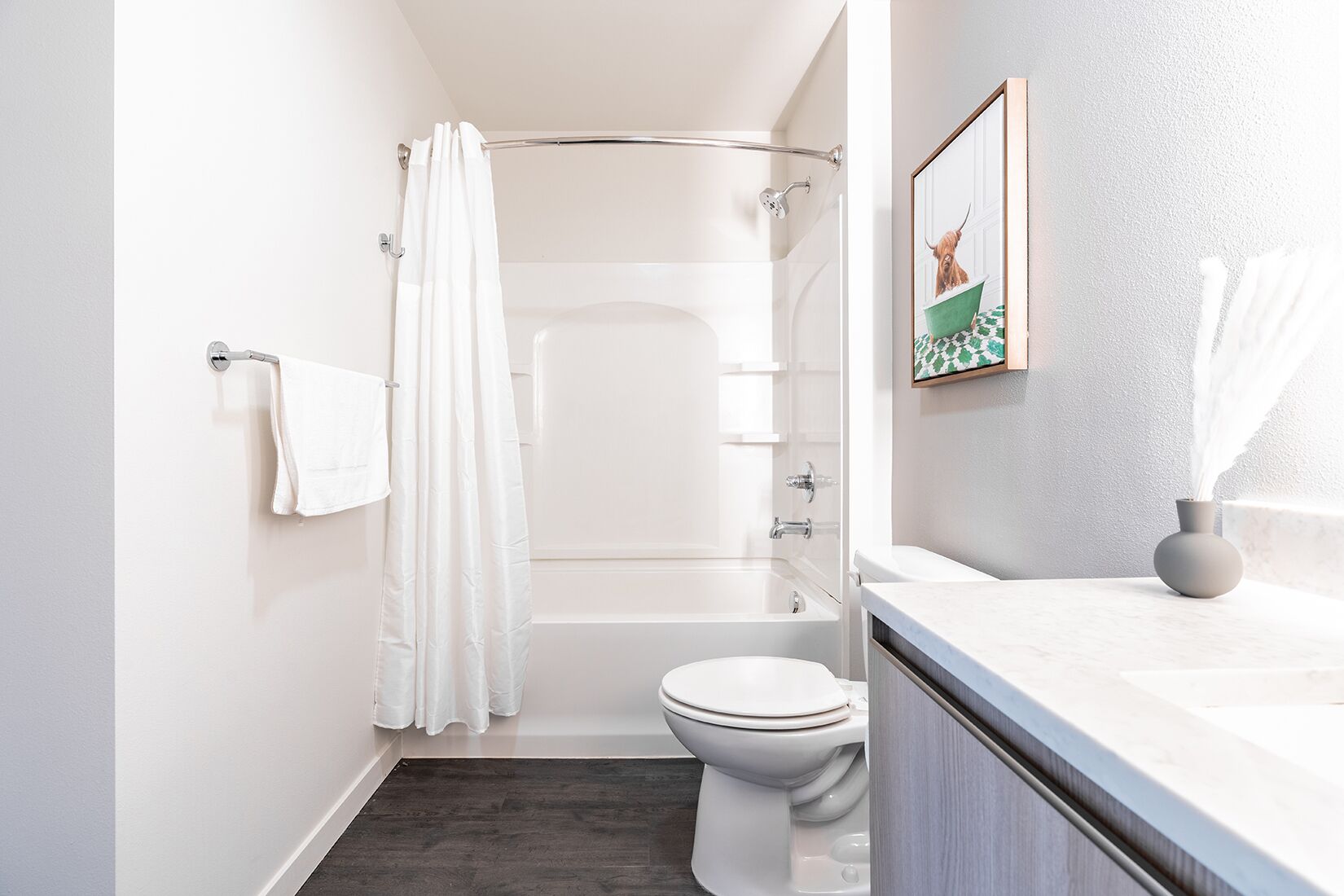 Un baño moderno con ducha, inodoro y tocador con un florero.