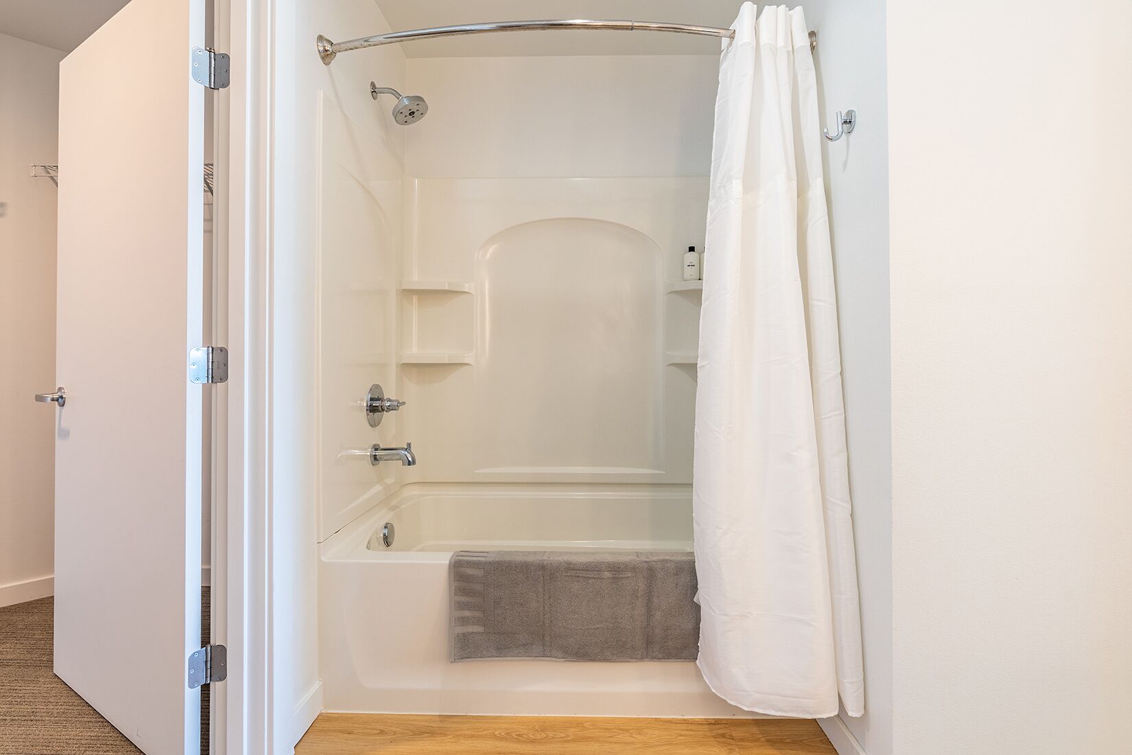 Una doccia a filo pavimento con vasca da bagno, un portascopevoli e un soffione.
