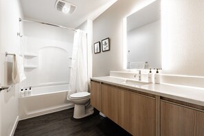A modern bathroom with a bathtub, toilet, and vanity. - Sophari Downtown: Bellevue Apartments (Bellevue)