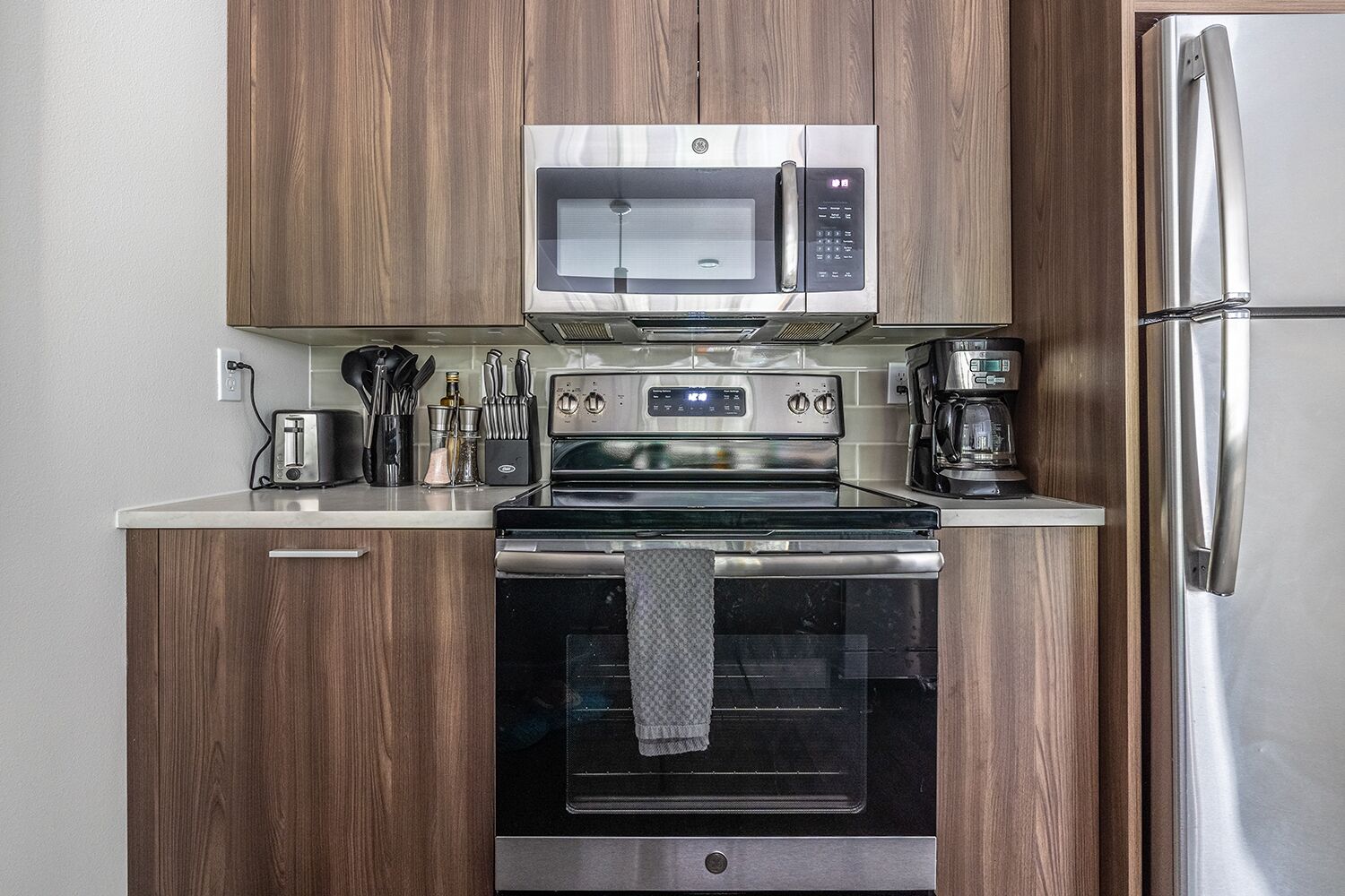 A compact kitchen with a microwave, oven, and refrigerator.