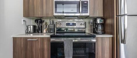 A compact kitchen with a microwave, oven, and refrigerator.
