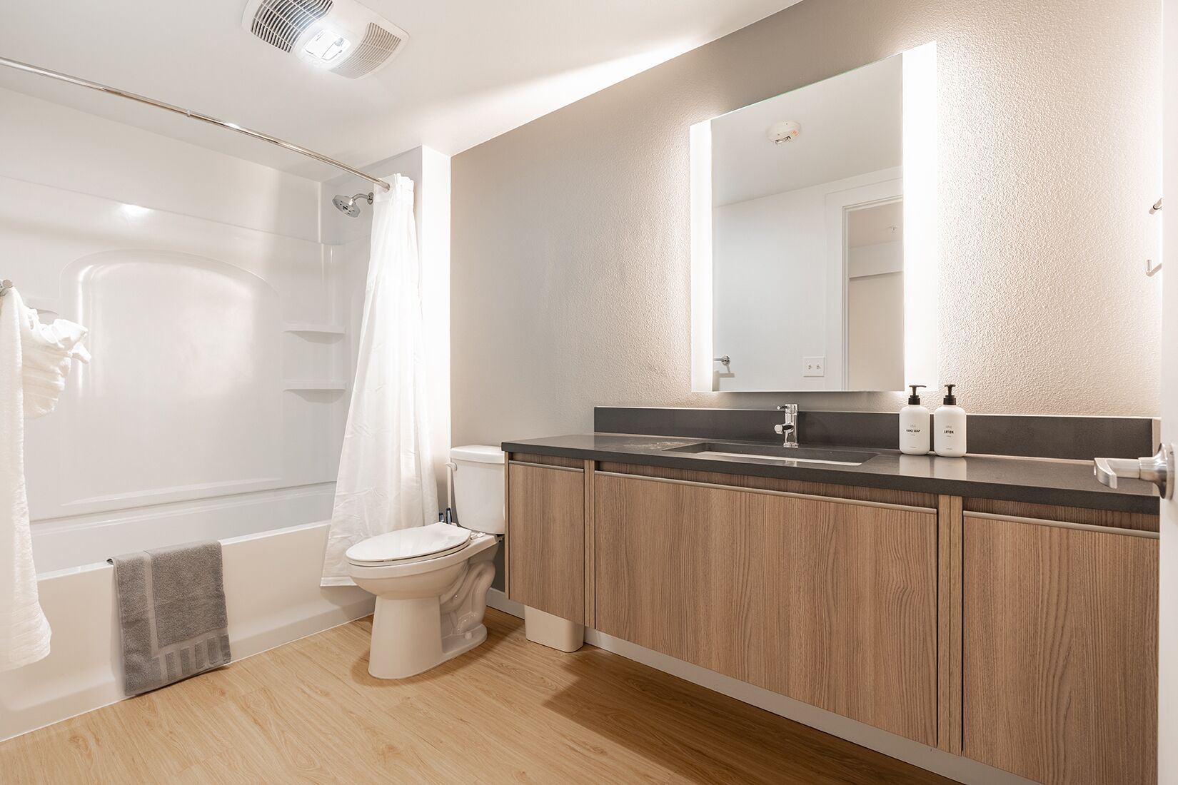 A modern bathroom with a shower, toilet, and vanity.