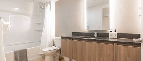 A modern bathroom with a shower, toilet, and vanity.