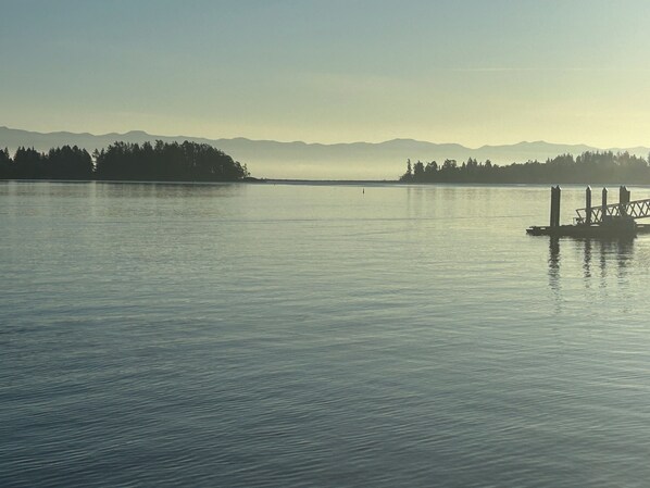 A calm lake with a dock and distant mountains.