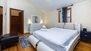 Un dormitori amb un llit gran, un aparador, un mirall i una finestra amb cortines.