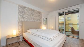 A modern bedroom with a large bed, bedside lamps, a patterned wall, and a sliding glass door to a balcony.