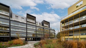 Un edificio moderno de varios pisos con balcones, ventanas amplias y cielo despejado.