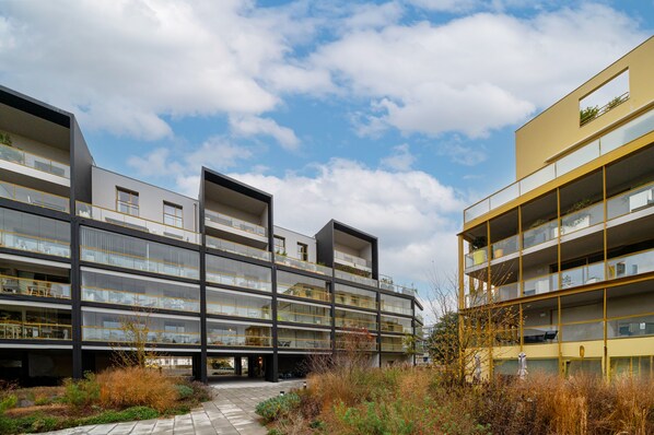 A modern multi-story building with balconies, large windows, and a clear sky.