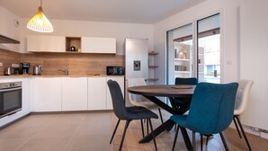 Una cocina moderna con armarios blancos, un microondas integrado y un dispensador de agua. Hay un comedor con una mesa redonda y sillas.