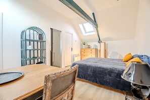 A bedroom with a bed, a desk, a chair, a dresser, and a skylight.
