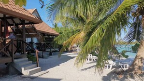 A beachside resort with a covered area, palm trees, and a view of the sea. - Flyfishing Anaa Toku Kaiga (Anaa)