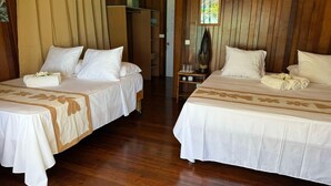 Two double beds with white linens and floral patterns, wooden flooring, and a wooden headboard. - Flyfishing Anaa Toku Kaiga (Anaa)
