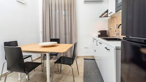 Una cocina compacta con una mesa de comedor, sillas, refrigerador y microondas.