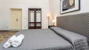 Habitación de hotel con cama, armario, puerta, lámpara y un cuadro en la pared.