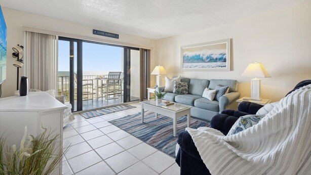 A hotel room with a balcony, a sofa, a coffee table, and a view of the ocean. - Relax and Unwind Direct Ocean View with Heated Pool & Hot Tub (Cocoa Beach)