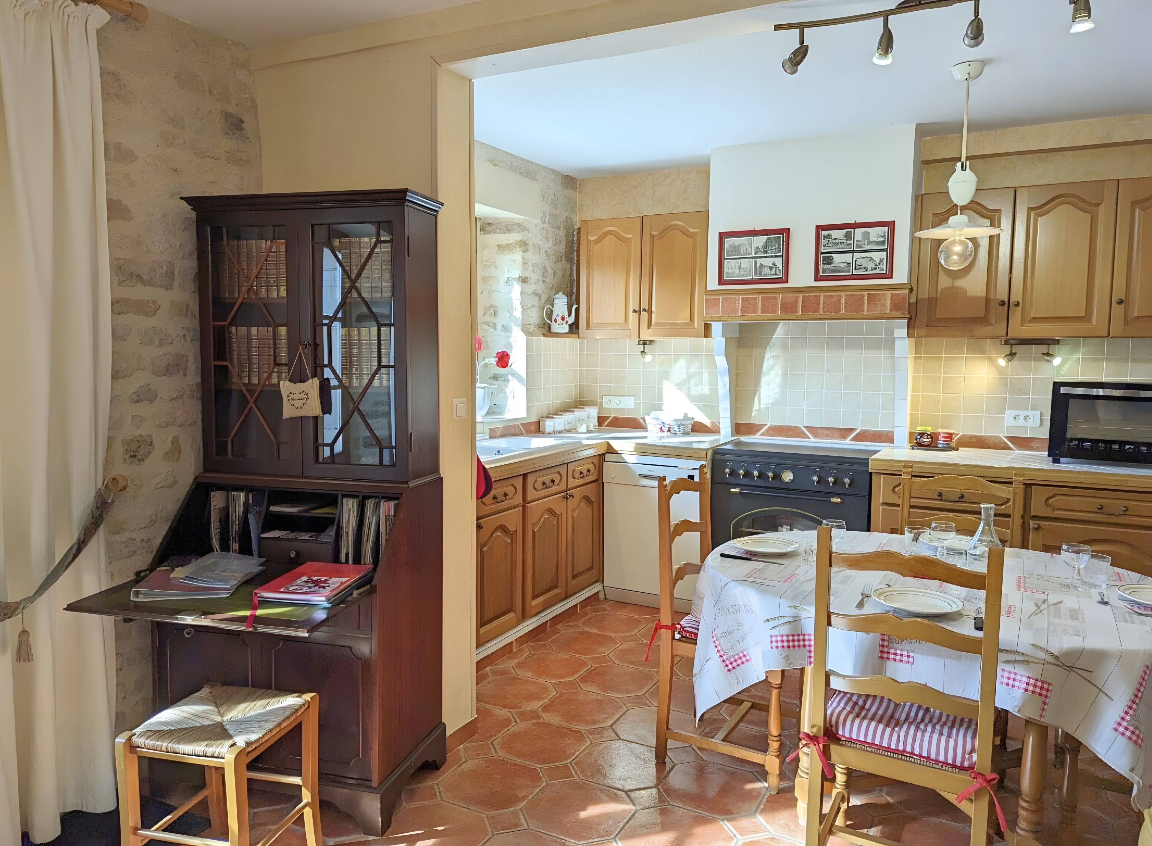 Cozinha com armários de madeira, fogão, micro-ondas e área de jantar com mesa posta para dois.