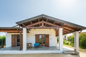 Un espacio al aire libre cubierto con techo de madera, una mesa y una silla azul.