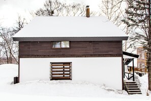 Una casa di legno con facciata bianca, un camino e una piccola finestra.