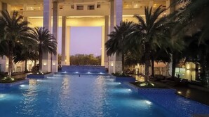 A large indoor swimming pool with palm trees and a view of a building in the background. - New City Thu Thiem D2 (Ho Chi Minh City)