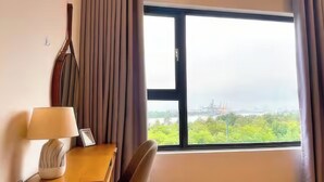 A hotel room with a large window, a desk with a lamp, and a chair. - New City Thu Thiem D2 (Ho Chi Minh City)