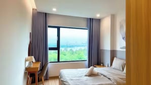 A hotel room with a large window, a bed, a bedside table, and a chair. - New City Thu Thiem D2 (Ho Chi Minh City)