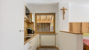 A narrow kitchen with a wooden window, a radiator, and a crucifix on the wall.