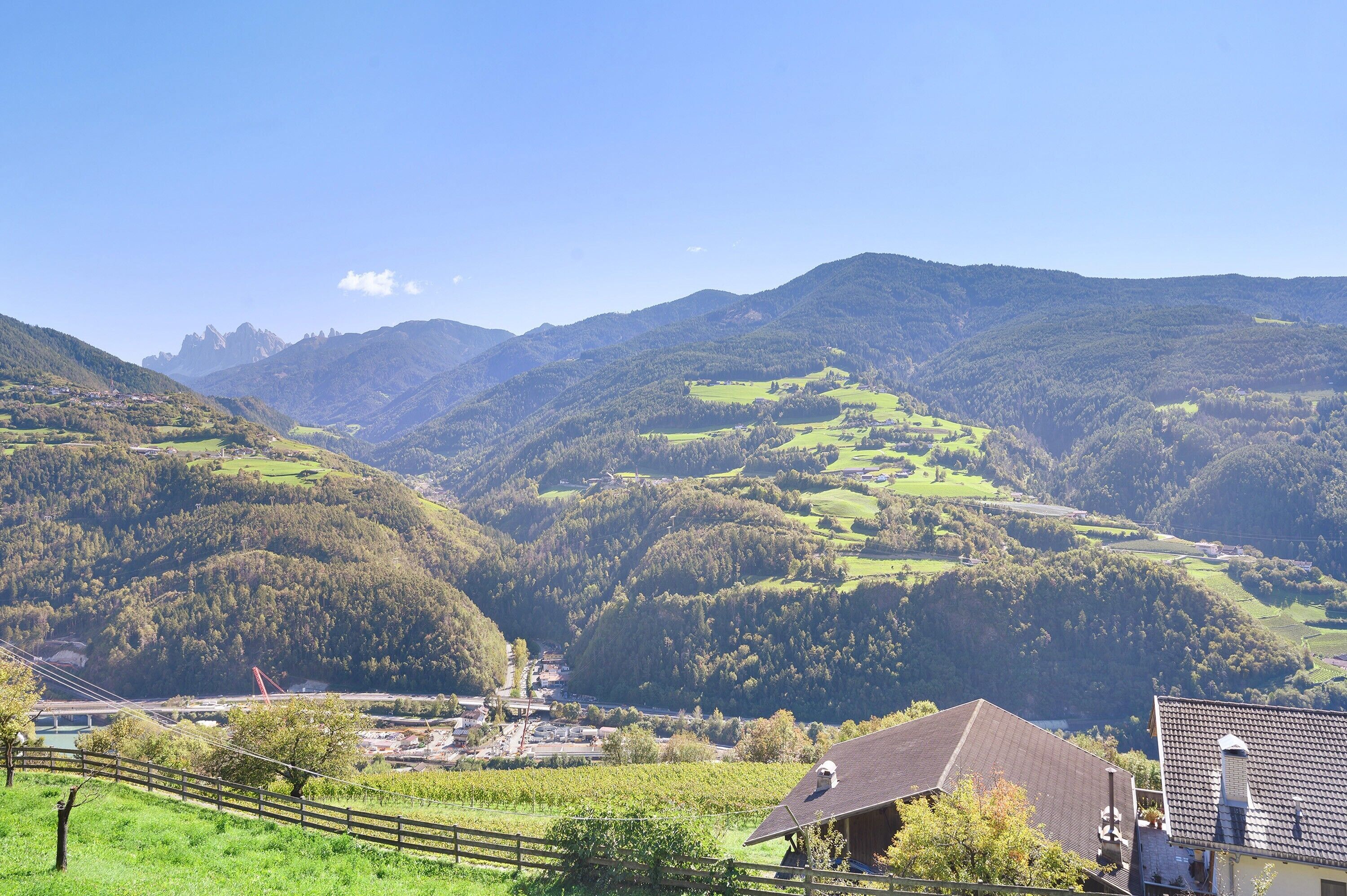 A rural landscape with a valley, hills, and a small settlement with buildings and a bridge.