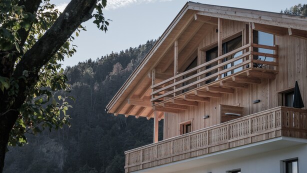 A wooden building with a balcony, a window, and a door.