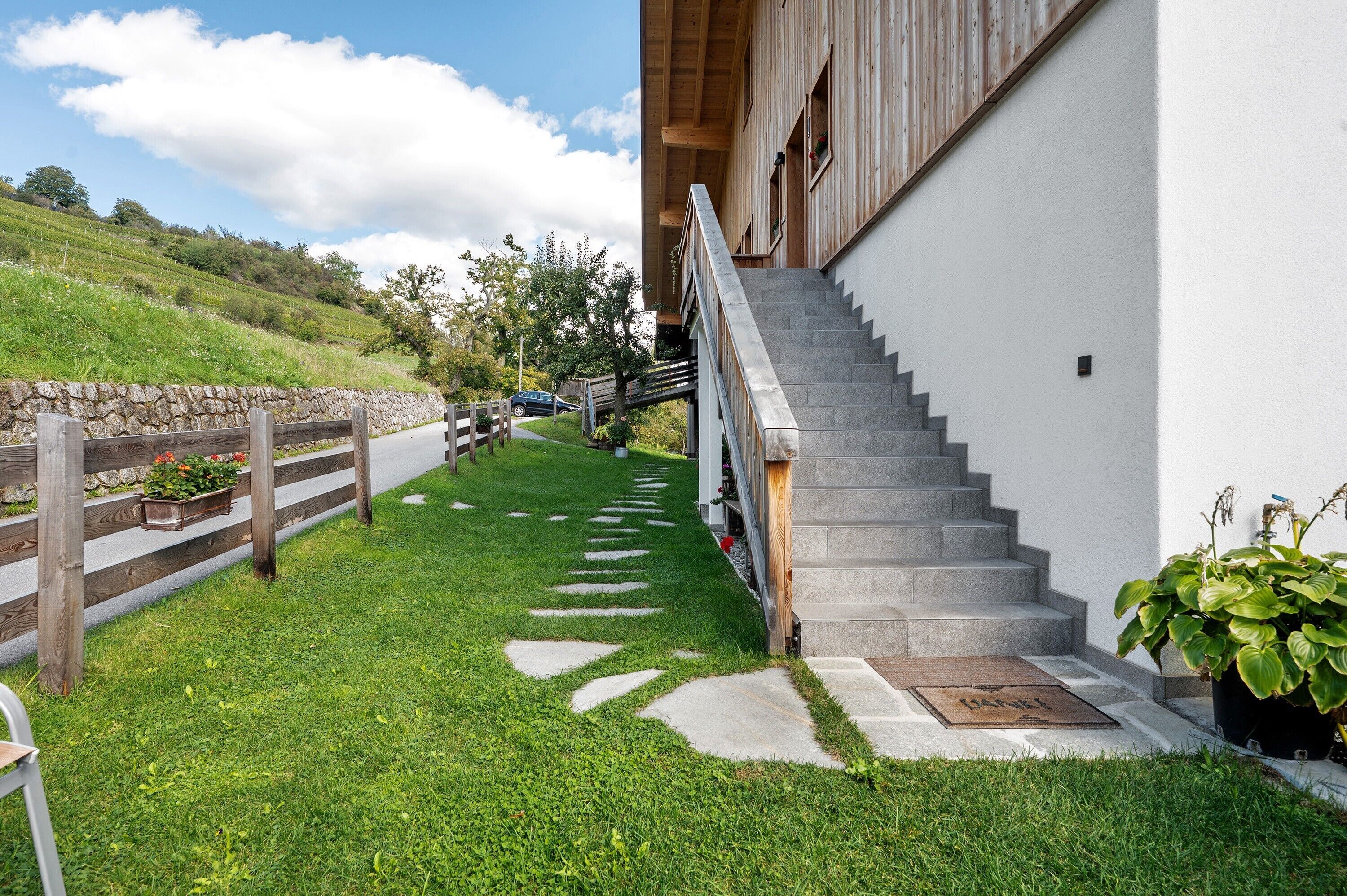 A staircase leading to a building with a stone wall and wooden fence.