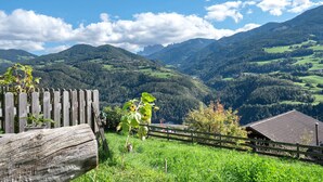 A wooden fence, a building, and a mountainous landscape.