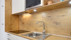 A kitchen with a wooden countertop, stainless steel sink, and white cabinetry.