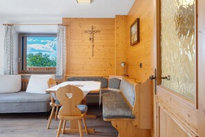 A wooden interior with a cross on the wall, a sofa, a table, and benches.