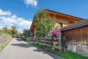 A wooden building with a sloped roof, a stone wall, and a wooden fence.