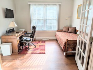 A bedroom with a bed, desk, chair, and a window.