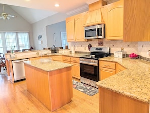 A kitchen with granite countertops, wooden cabinets, a stainless steel oven, and a microwave.