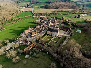 Vista aérea de una finca histórica con un patio central, edificios circundantes y amplios campos verdes.