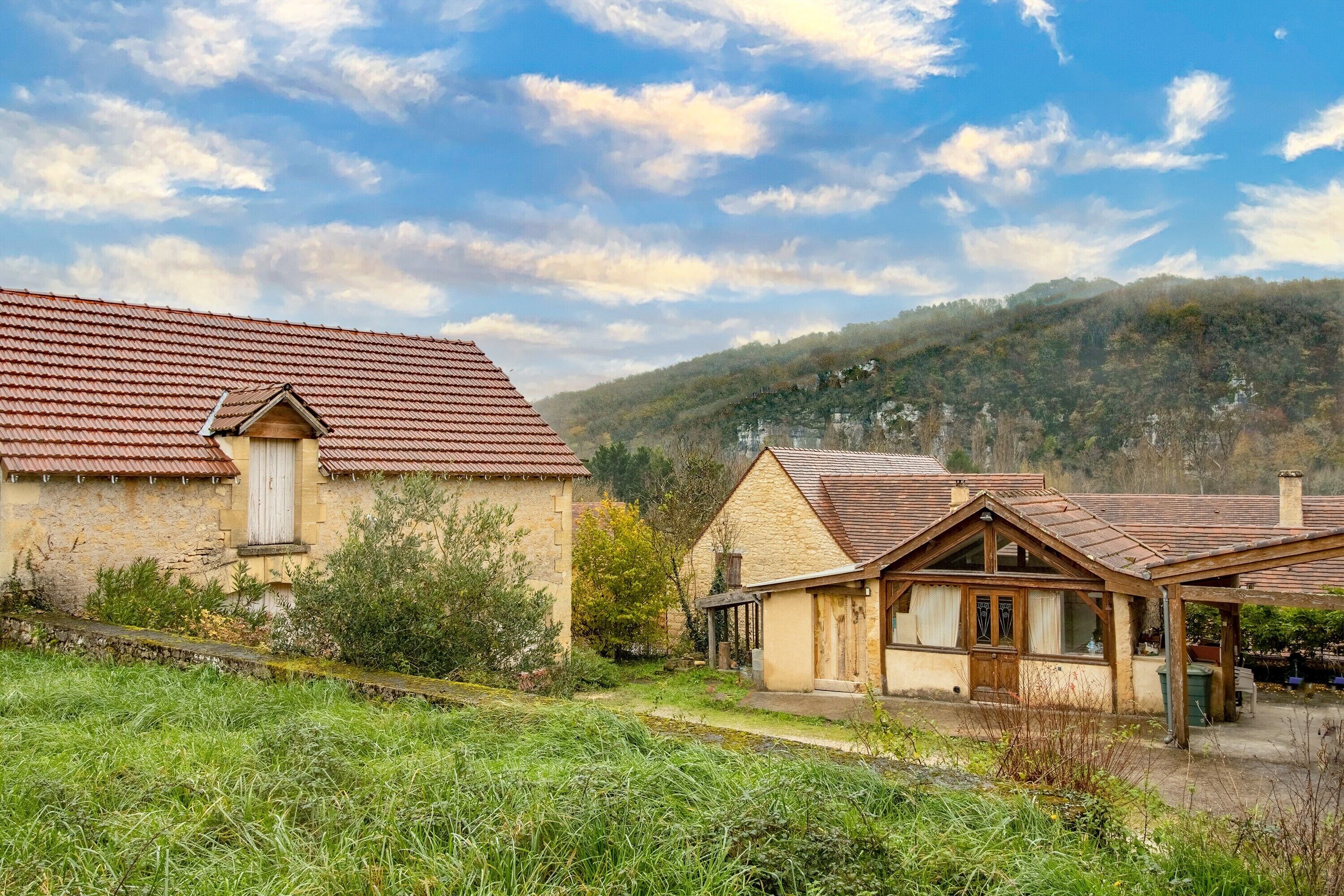 Una casa di campagna con tetto in tegole rosse, pareti in pietra e un piccolo portico.